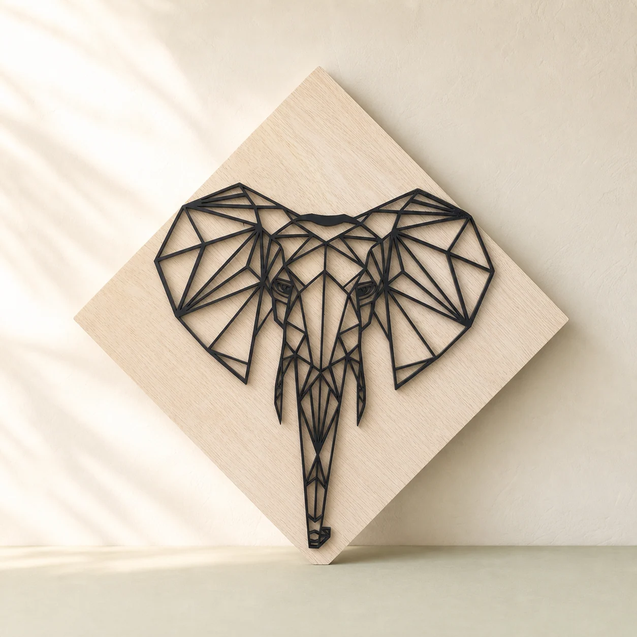 Cap de elefant geometric din contururi negre de lemn, așezat pe un panou deschis